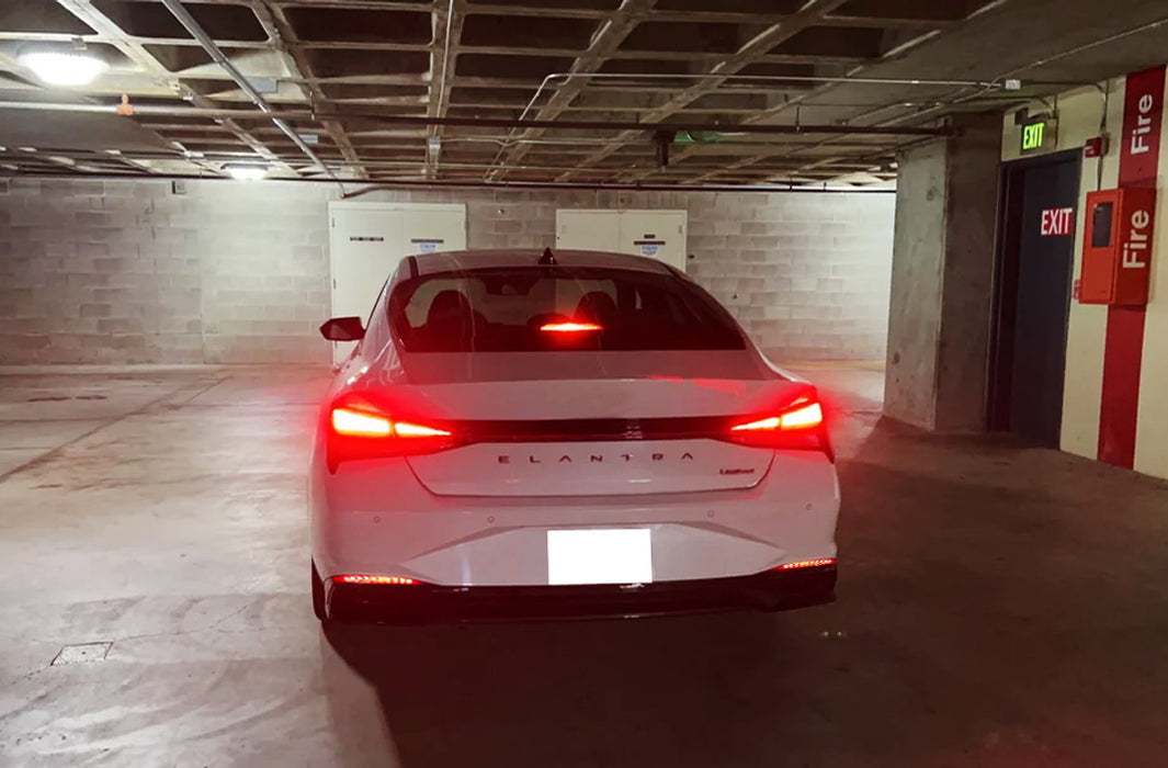 White car parked in a garage with red tail lights on.